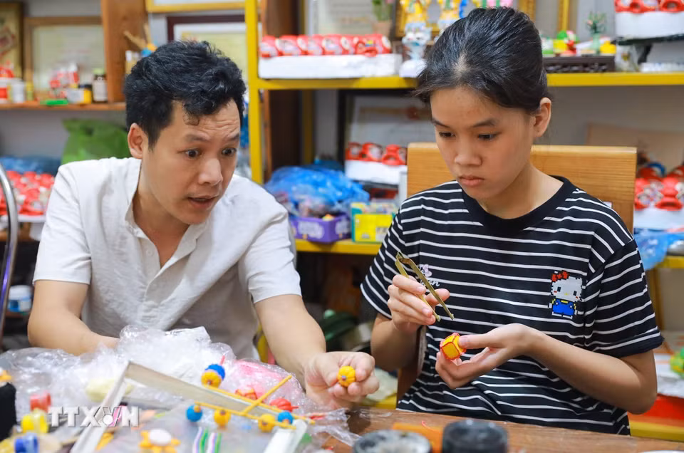 Nghệ nhân Đặng Văn Hậu tận tình chỉ dạy, hướng dẫn cho các bạn trẻ thực hiện tác phẩm tò he. (Ảnh: Khánh Hòa/TTXVN)