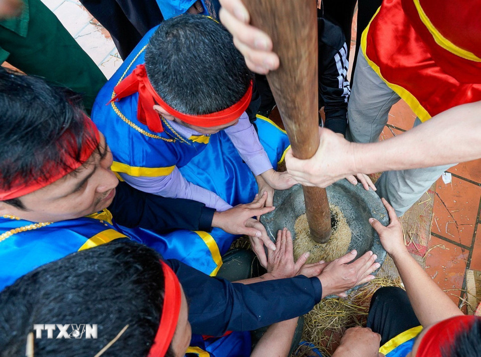 Các nam thanh niên trong đội giã thóc bằng cối đá. (Ảnh: Khánh Hòa/TTXVN)