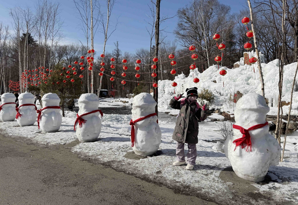 Trẻ em thích thú khi chụp ảnh với người tuyết tại Trường Bạch Sơn. (Ảnh: Công Tuyên/ TTXVN)