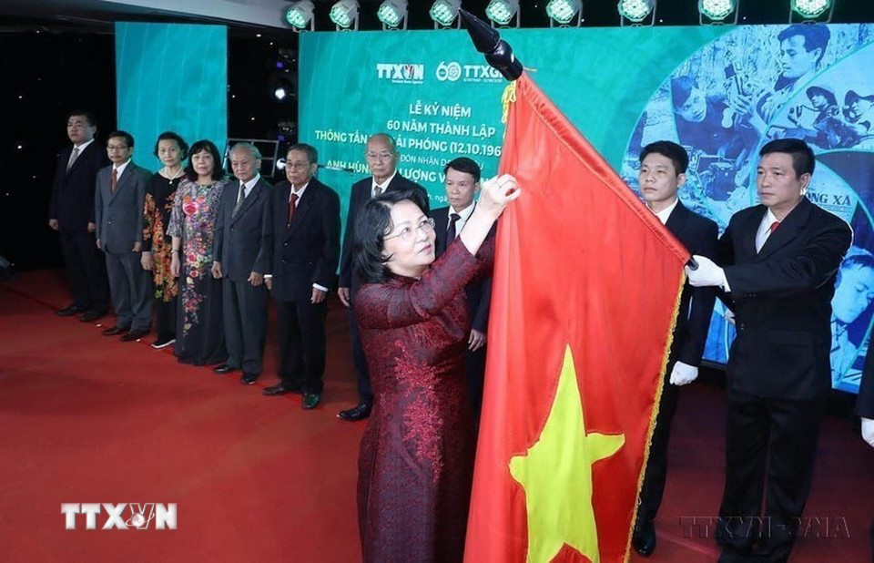 Thừa ủy quyền của Chủ tịch nước, Phó Chủ tịch nước Đặng Thị Ngọc Thịnh gắn danh hiệu Anh hùng Lực lượng vũ trang nhân dân tặng Thông tấn xã Giải phóng lên lá cờ truyền thống của TTXVN tại Lễ kỷ niệm 60 năm Ngày thành lập TTXGP (12/10/1960-12/10/2020). (Ảnh: Lâm Khánh/TTXVN)