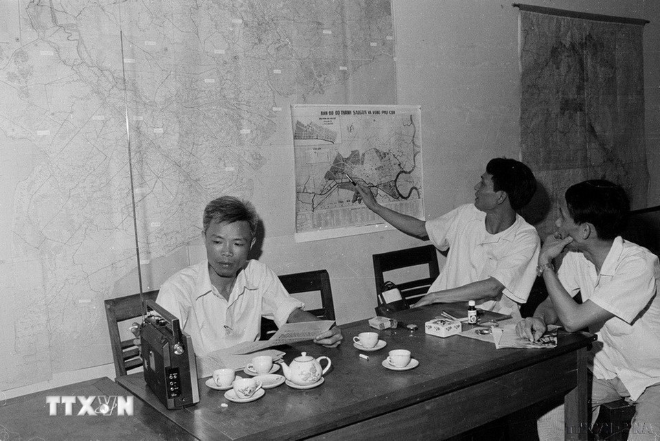 Quá trình hình thành và phát triển của TTXVN luôn đồng hành với sự nghiệp cách mạng, giải phóng dân tộc và dựng xây đất nước. Trong các cuộc kháng chiến thống nhất và bảo vệ Tổ quốc, đội ngũ đông đảo những người làm báo của TTXVN đã thực sự là những nhà báo-chiến sỹ. Trong ảnh: Phó Tổng Giám đốc Thông tấn xã Việt Nam Đỗ Phượng theo dõi tình hình chiến trường trên bản đồ Sài Gòn (1975). (Ảnh: TTXVN)