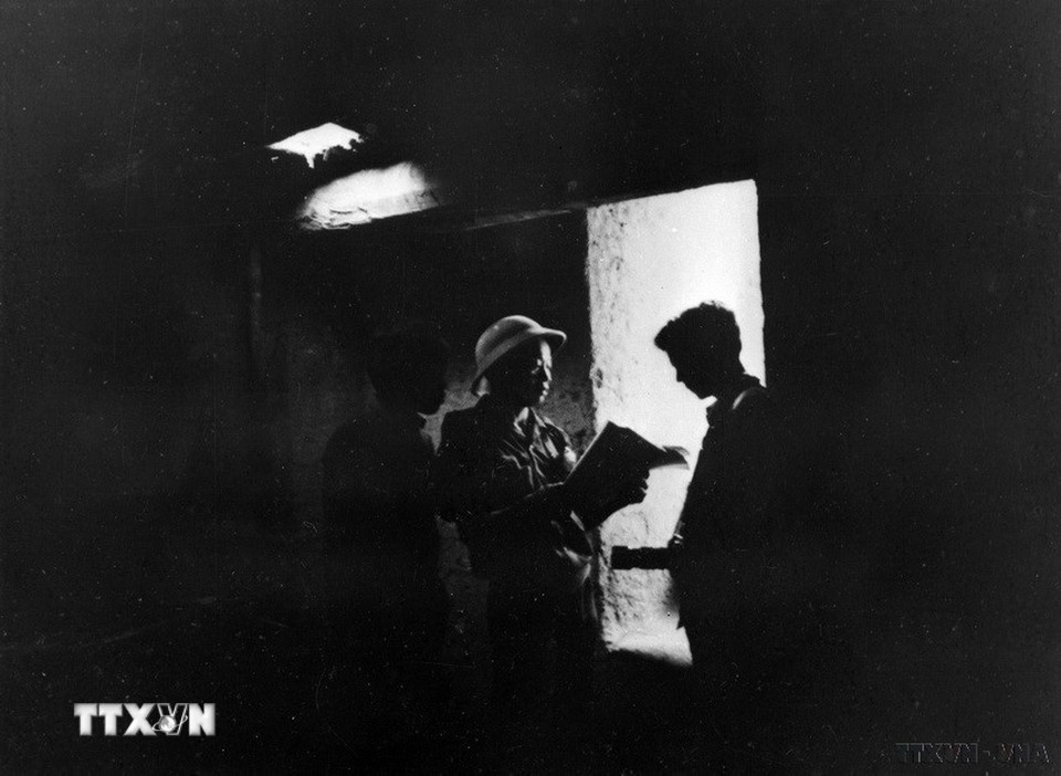 Hai phóng viên nhiếp ảnh TTXGP Nguyễn Chí Anh và Nông Quang Khanh xem tài liệu ở dưới hầm bí mật Củ Chi trong chuyến đi công tác tháng 3/1973. (Ảnh: Phong Vân/TTXVN)
