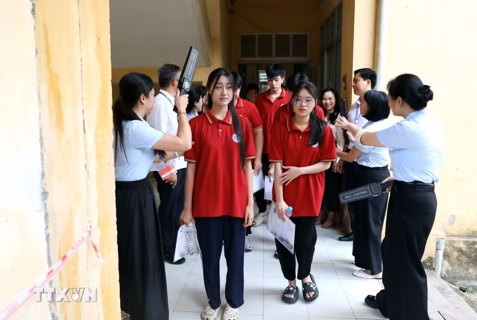 Cán bộ coi thi trường Trung học Phổ thông Tân Trào, phường Minh Xuân (Tuyên Quang) kiểm tra thí sinh trước khi vào phòng thi. (Ảnh: Quang Cường/TTXVN)