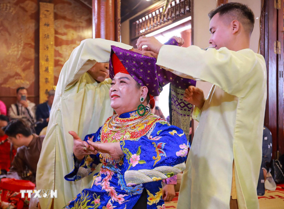 Trong nghi thức hầu đồng, các đồng thầy và thanh đồng được đệ tử chuẩn bị và thay trang phục trực tiếp cho các giá đồng tiếp theo. (Ảnh: Khánh Hòa/TTXVN)