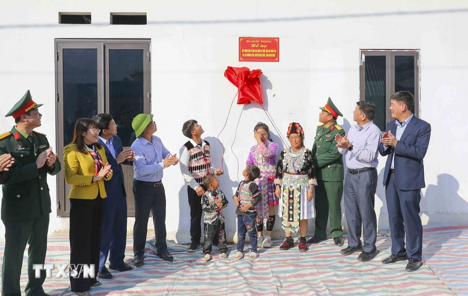 Đại biểu và người dân cùng kéo biển khánh thành nhà ở mới. (Ảnh: Xuân Tư/TTXVN)