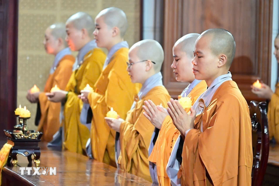 Các chư ni Học viện Phật giáo Việt Nam tại Hà Nội thắp nến cầu nguyện quốc thái dân an. (Ảnh: TTXVN phát)