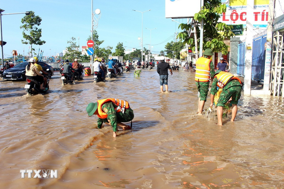 Lực lượng bộ đội Đồn biên phòng Thanh Hải khơi thông cống rãnh thoát nước tại tuyến đường bị ngập Nguyễn Thông, phường Phú Thủy (Lâm Đồng). (Ảnh: Hồng Hiếu /TTXVN)
