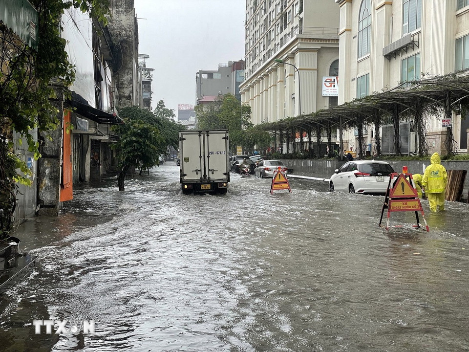 Nước ngập đến quá nửa bánh xe trên phố Mạc Thị Bưởi khiến các phương tiện lưu thông khó khăn. (Ảnh: Trần Việt/TTXVN)