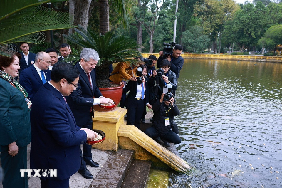 Thủ tướng Phạm Minh Chính và Thủ tướng Kyrgyzstan Adylbek Kasymaliev cùng cho cá ăn trong khu ao cá Bác Hồ. (Ảnh: Dương Giang/TTXVN)