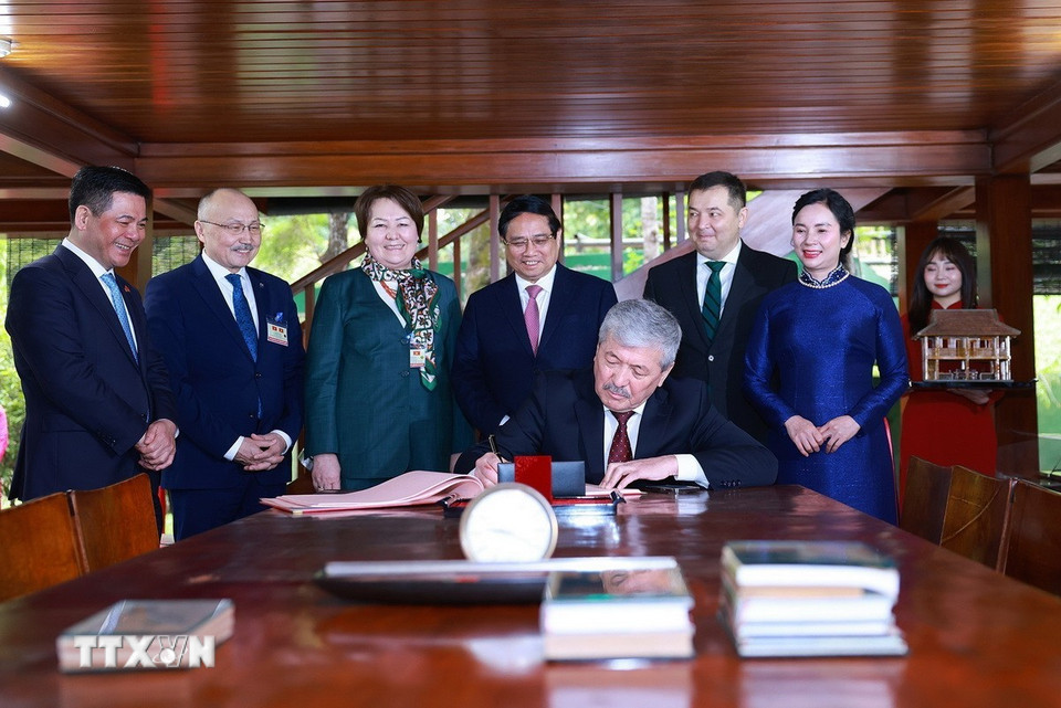 Thủ tướng Kyrgyzstan Adylbek Kasymaliev viết lưu bút khi đến thăm Di tích Bác Hồ. (Ảnh: Dương Giang/TTXVN)
