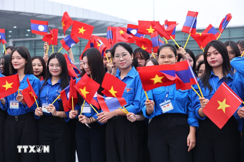 Học sinh, sinh viên thủ đô đón Tổng Bí thư Ban Chấp hành Trung ương Đảng Nhân dân cách mạng Lào, Chủ tịch nước Cộng hòa Dân chủ Nhân dân Lào Thongloun Sisoulith và Phu nhân tại sân bay Quốc tế Nội Bài. (Ảnh: Minh Đức/TTXVN)
