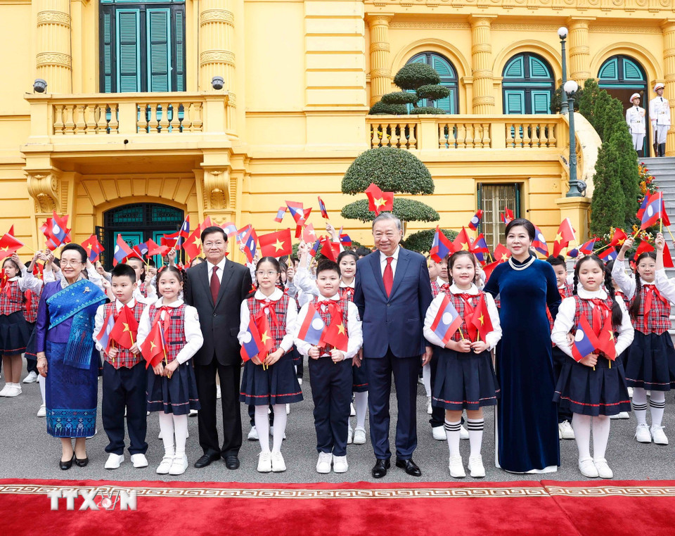 Tổng Bí thư Tô Lâm và Phu nhân cùng Tổng Bí thư, Chủ tịch nước Lào Thongloun Sisoulith và Phu nhân chụp ảnh chung với thiếu nhi Thủ đô tại lễ đón. (Ảnh: Thống Nhất/TTXVN)