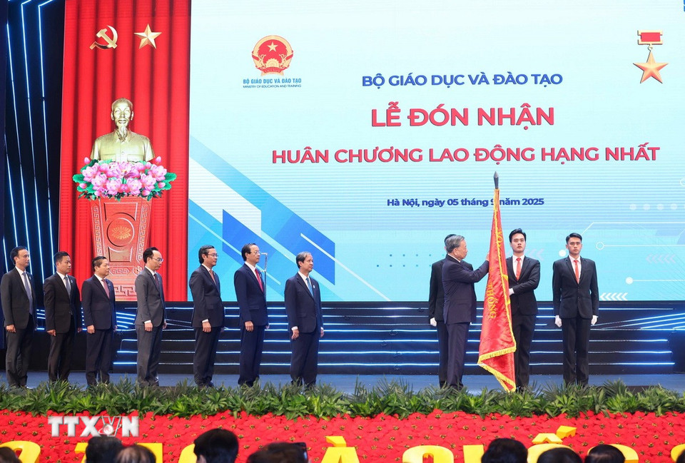 Tổng Bí thư Tô Lâm gắn Huân chương Lao động hạng Nhất lên lá cờ truyền thống của Bộ Giáo dục-Đào tạo. (Ảnh: Thống Nhất/TTXVN)