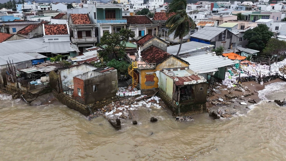 Sóng đánh làm sụt móng nhà dân tại cồn Nhất Trí, người dân dùng bao cát để gia cố. (Ảnh: Đặng Tuấn/TTXVN)