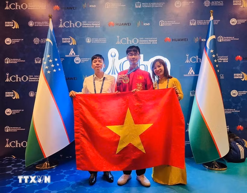 Thầy Nguyễn Đình Hùng, Hiệu trưởng Trường THPT Chuyên Vĩnh Phúc cùng cô giáo Phùng Thị Nga, giáo viên trực tiếp phụ trách đội tuyển và em Đinh Xuân Phúc tại Lễ trao giải Kỳ thi Olympic Hóa học Quốc tế năm 2026, diễn ra tại Uzbekistan. (Ảnh: TTXVN phát)