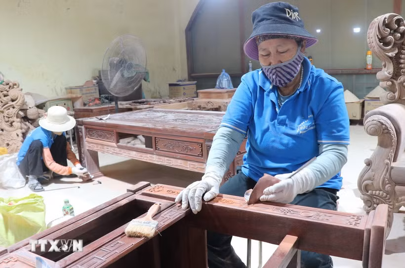 Những người thợ tỷ mỉ, cẩn thận đánh giấy giáp cho gỗ lỳ, bóng. (Ảnh: Thanh Thương/TTXVN)