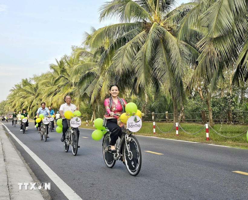 Du khách trải nghiệm "du lịch xanh" dưới tán dừa trên các cung đường phường An Hội, tỉnh Vĩnh Long. (Ảnh: Chương Đài/TTXVN)