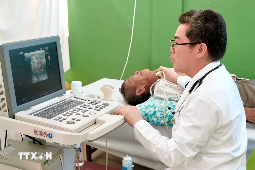 Bác sỹ Tôn Thanh Trà, Giám đốc Bệnh viện Chợ Rẫy - Phnom Penh trực tiếp thăm khám, siêu âm một trường hợp bệnh nhân bệnh nặng, tiếp nhận phẫu thuật miễn phí tại bệnh viện. (Ảnh: Quang Anh/TTXVN)