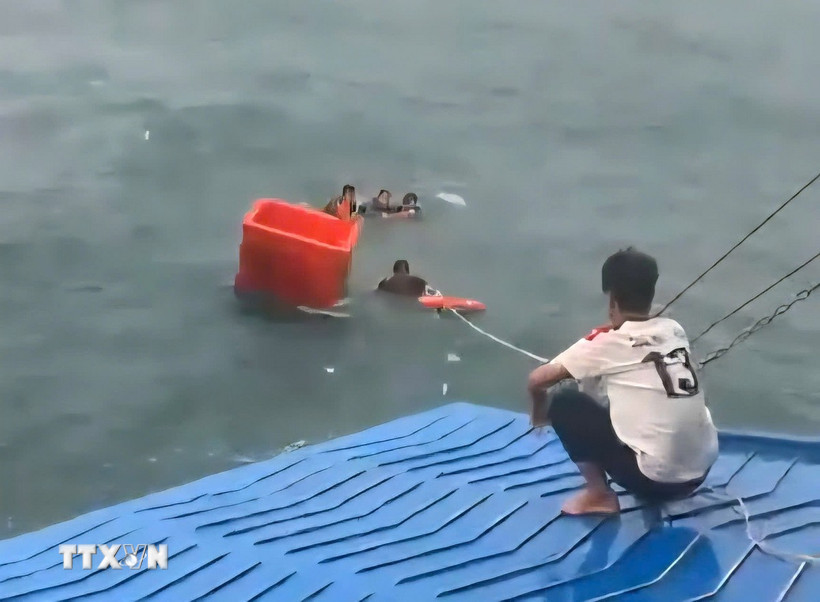 Thủy thủ và thuyền viên cứu ngư dân gặp nạn trên biển. (Ảnh: TTXVN phát)