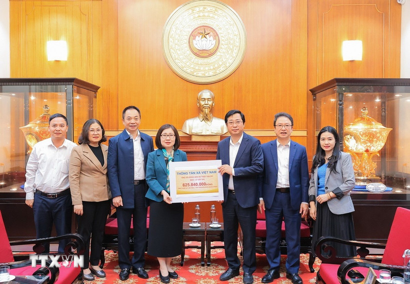 Bà Đoàn Thị Tuyết Nhung, Ủy viên Ban Thường vụ Đảng ủy, Phó Tổng giám đốc TTXVN trao ủng hộ cho đại diện Uỷ ban Trung ương Mặt trận Tổ quốc Việt Nam, ông Cao Xuân Thạo, Uỷ viên Đoàn chủ tịch, Trưởng Ban công tác Xã Hội. (Ảnh: Lê Đông/TTXVN)