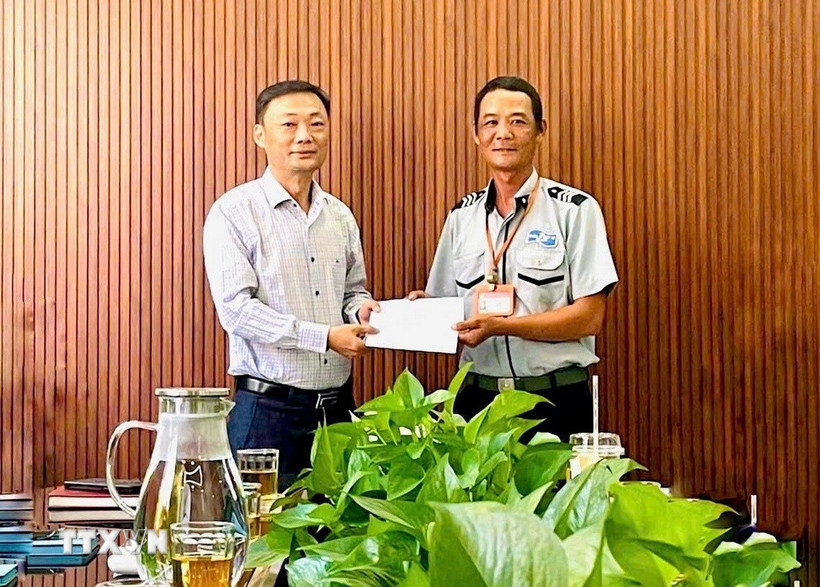 Ông Nguyễn Đức Vũ Trưởng Ban Quản lý đã trao giấy khen và khen thưởng đột xuất cho anh Phan Thanh Trinh (phải). (Ảnh: TTXVN phát).