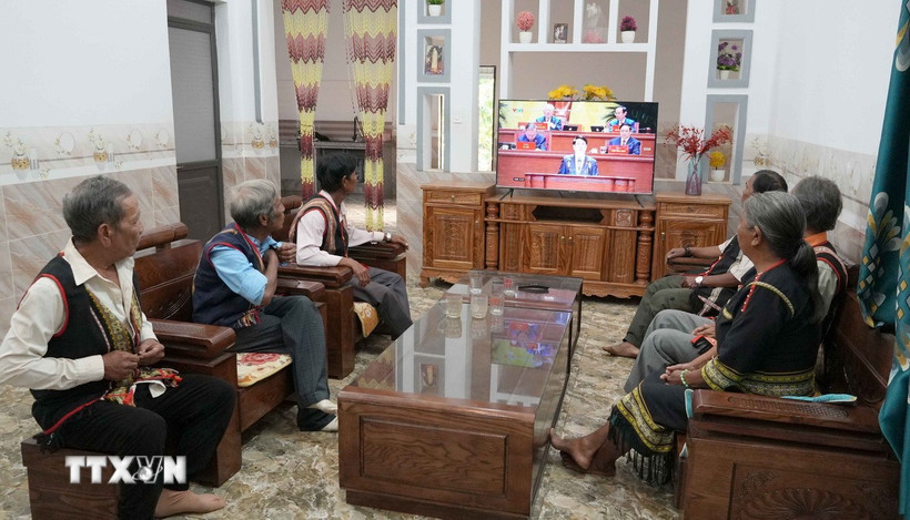 Già làng, người có uy tín và bà con làng Plei Jơ Drơp, xã Ia Chim, tỉnh Quảng Ngãi theo dõi phiên khai mạc Đại hội lần thứ XIV của Đảng. (Ảnh: Cao Nguyên/TTXVN)