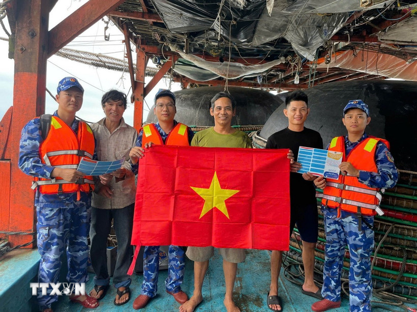 Cán bộ chiến sỹ Vùng Cảnh sát biển 2 kết hợp tuyên truyền với tặng hàng nghìn cờ Tổ quốc cho ngư dân làm ăn trên biển. (Ảnh: Đoàn Hữu Trung/TTXVN)