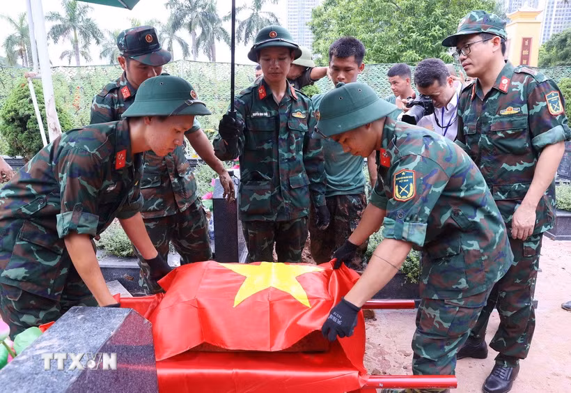 Thực hiện nghi thức phủ Quốc kỳ trang trọng, tri ân Anh hùng liệt sỹ đã hy sinh vì độc lập, tự do của Tổ quốc tại Nghĩa trang Mai Dịch (phường Phú Diễn). (Ảnh: Văn Điệp/TTXVN)