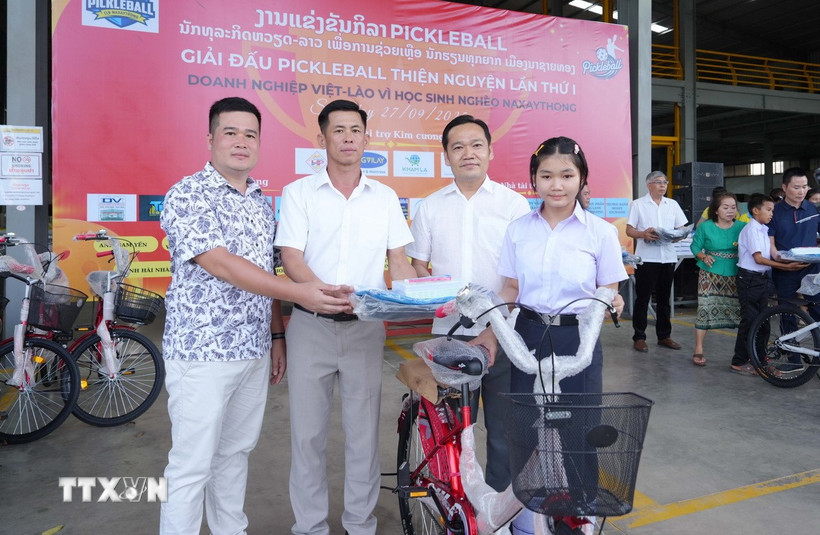 Chủ tịch huyện Naxaithong và Chủ tịch Câu lạc bộ Doanh nghiệp tỉnh Nghệ An tại huyện Naixaithong, thủ đô Viêng Chăn, trao quà cho học sinh nghèo vượt khó. (Ảnh: Xuân Tú/TTXVN)