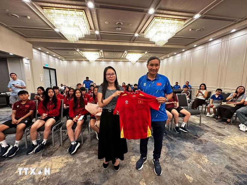 Huấn luyện viên Mai Đức Chung (phải) tặng áo thi đấu có chữ ký của các cầu thủ đội tuyển cho Tổng Lãnh sự Nguyễn Thanh Hà. (Ảnh: Thanh Tú/TTXVN)