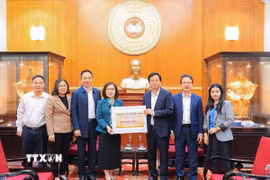 Bà Đoàn Thị Tuyết Nhung, Ủy viên Ban Thường vụ Đảng ủy, Phó Tổng giám đốc TTXVN trao ủng hộ cho đại diện Ủy ban Trung ương Mặt trận Tổ quốc Việt Nam, ông Cao Xuân Thạo, Ủy viên Đoàn chủ tịch, Trưởng Ban công tác Xã Hội. (Ảnh: Lê Đông/TTXVN)