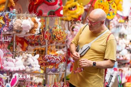 Du khách nước ngoài lựa chọn cho mình món đồ Trung thu trên phố Hàng Mã. (Ảnh: Khánh Hòa/TTXVN)