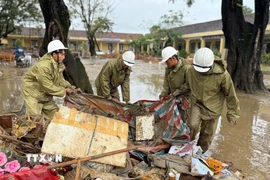 Lực lượng Quân đội hỗ trợ người dân thu dọn rác và bùn đất sau khi nước rút. (Ảnh: Nguyên Dung/TTXVN)