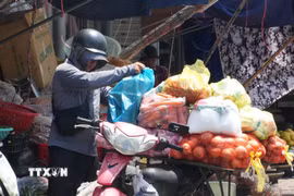 Người dân sắp xếp, vận chuyển hàng hóa dưới nắng nóng gay gắt ở khu vực chợ Đông Ba, phường Phú Xuân, thành phố Huế. (Ảnh: Nguyên Lý/TTXVN)