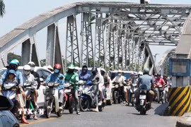 Người dân mặc đồ bảo hộ chống nắng nóng khi tham gia giao thông trên cầu Trường Tiền, thành phố Huế. (Ảnh: Nguyên Lý/TTXVN)