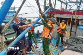 Lực lượng Đồn Biên phòng Quỳnh Phương (Bộ đội biên phòng tỉnh Nghệ An) hỗ trợ ngư dân chằng buộc trên tàu đánh cá trước cảnh báo bão, ngày 21/7/2025. (Ảnh: TTXVN phát)