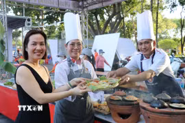 Du khách thích thú trải nghiệm món "bánh xèo ngàn năm" được làm bởi các đầu bếp chuyên nghiệp đến từ Thành phố Hồ Chí Minh. (Ảnh: Nguyễn Thành/TTXVN)