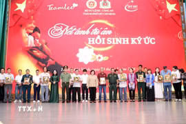 Lãnh đạo Thành ủy, Bộ Tư lệnh Thành phố, Công an Thành phố cùng nhóm phục dựng ảnh "Team Lee" trao tặng di ảnh liệt sỹ đã phục dựng cho thân nhân các liệt sỹ. (Ảnh: Xuân Khu/TTXVN)