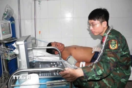 Bác sỹ quân y tiến hành siêu âm ổ bụng cho ngư dân Trần Công Nhanh. (Ảnh: TTXVN phát)