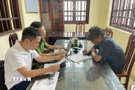 Đối tượng T.V.H (phải) thừa nhận hành vi vi phạm của mình tại cơ quan công an. (Ảnh: TTXVN phát)