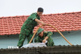 Các cán bộ chiến sỹ Đồn biên phòng Đức Minh giúp người dân xã Mỏ Cày (Quảng Ngãi) gia cố nhà cửa trước bão số 13. (Ảnh: Phạm Cường/TTXVN)