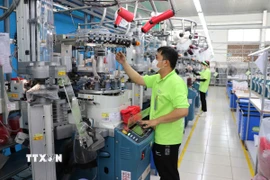 Công nhân nhà máy Sung Hwa Vina (vốn Hàn Quốc) tại Khu Công nghiệp Hòa Bình (Tây Ninh) kiểm tra sợi trên máy dệt tất. (Ảnh: Minh Hưng/TTXVN)