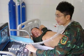 Bác sỹ Trung tâm y tế thị trấn Trường Sa siêu âm ổ bụng cho bệnh nhân Võ Sỹ Danh. (Ảnh: TTXVN phát)