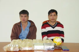 Hai đối tượng cùng tang vật vụ án. (Ảnh: TTXVN phát)