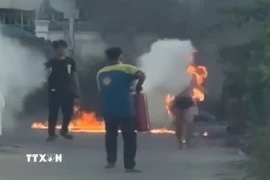 Người dân dùng bình chữa cháy cứu nạn nhân. (Ảnh: TTXVN phát)