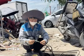 Người lao động phải làm việc ngoài trời dưới nền nhiệt gần 40 độ C. (Ảnh: Quốc Lũy/ TTXVN)
