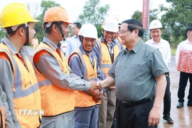 Thủ tướng Phạm Minh Chính với công nhân thi công dự án Đường tỉnh ĐT.975 (đoạn từ ĐT 973 - Cảng Hàng không Phú Quốc). (Ảnh: Dương Giang/TTXVN)