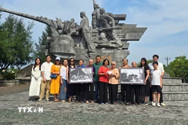 Gia đình nhà báo, liệt sỹ Lương Nghĩa Dũng tặng các nữ pháo thủ của Đại đội nữ pháo binh Ngư Thủy 2 bức ảnh tư liệu. (Ảnh: TTXVN phát)