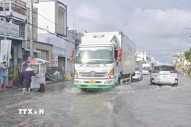 Các phương tiện giao thông di chuyển chậm trên tuyến đường ngập sâu. (Ảnh: Chanh Đa/TTXVN)