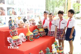 Các học sinh tham quan, tìm hiểu mão, mặt nạ của đồng bào Khmer. (Ảnh: Thanh Hòa/TTXVN)